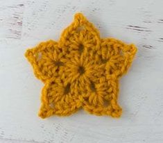 a yellow crocheted star ornament sitting on top of a white table