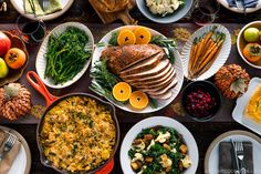 a table filled with lots of different types of food on plates and serving utensils