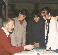 four young men standing around a table looking at papers