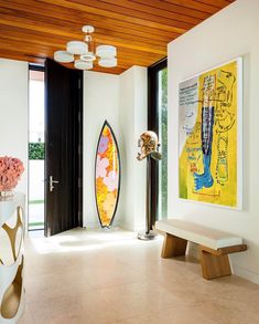 a surfboard sitting in the corner of a room next to a vase with flowers