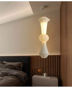 a bed room with a neatly made bed and a light hanging from the ceiling above it