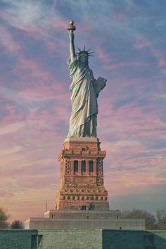 the statue of liberty in new york city, ny at sunset with pink and blue sky