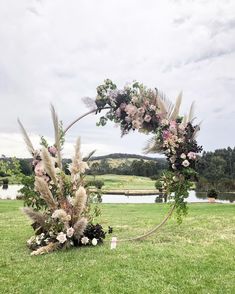 a wedding arch decorated with flowers and pamodia in the middle of a field