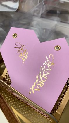 a close up of a pink paper with gold writing on it in a metal container