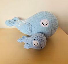 two blue stuffed animals sitting on top of a wooden table next to a white wall