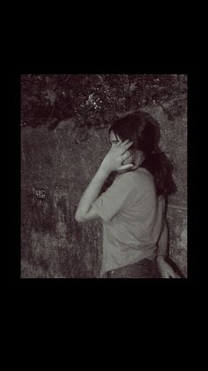 a woman leaning against a wall with her head in her hands