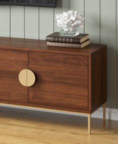 a wooden sideboard with two books on top and a vase filled with white flowers