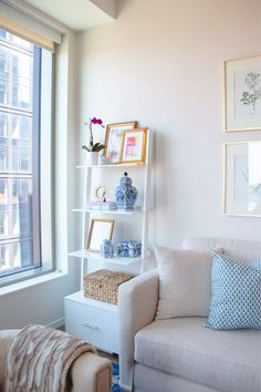 a white couch sitting next to a window in a living room with pictures on the wall