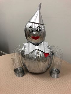 a silver tin can with a red heart on it's chest and wearing a hat