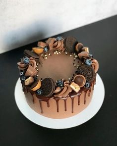 a chocolate cake topped with cookies and oreos on top of a white platter