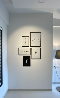 a white room with four black and white pictures on the wall next to a lamp