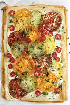 a square pizza with tomatoes, cheese and herbs on it is ready to be eaten