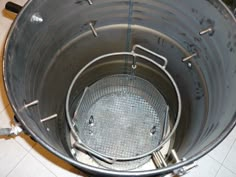 a large metal bucket sitting on top of a tiled floor