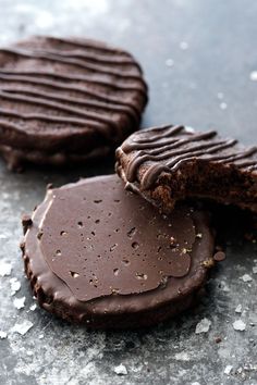 two cookies with chocolate frosting are on the table and one is broken in half