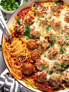 a bowl filled with pasta and meatballs covered in sauce, parmesan cheese and parsley