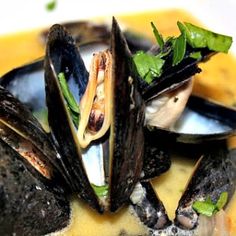 steamed mussels with sauce and greens in a bowl