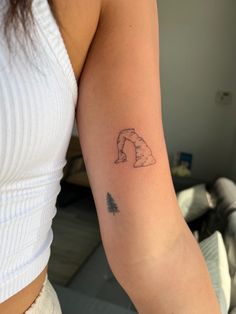 a woman's arm with a small tattoo of a polar bear and a pine tree