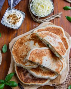 several pancakes stacked on top of each other next to bowls of cheese and sauces