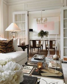 a living room filled with furniture and lots of white flowers on top of a coffee table