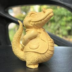 a small yellow figurine sitting on top of a car dashboard