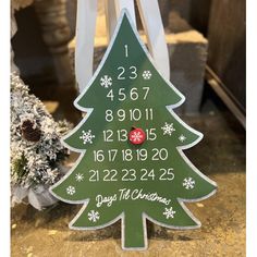 a wooden christmas tree with the date and time on it in front of snow covered trees