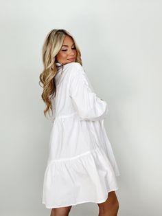 Indulge in luxury with our Collared Button Up Mini Dress. With its collared neckline, button closures, and ruched sleeves, this dress provides an elevated and trendy look. The mini and tiered design is perfect for any occasion, from brunch dates to elegant dinners. Its bright and versatile style is a must-have for your wardrobe, whether for a bridal event or a basic yet sophisticated look. Self 60% Cotton 40% Polyester Hand wash cold. Elegant Tiered Dress With Gathered Sleeves, Feminine Ruffled Shirt Dress For Daywear, Elegant Ruffled Shirt Dress For Daywear, Chic Tiered Dress With Gathered Sleeves, Elegant Ruffled Shirt Dress For Work, Elegant Mini-length Tiered Dress With Ruffle Hem, Button-up Ruffle Hem Dress For Daywear, Ruffle Hem Button-up Dress For Daywear, Chic White Ruffled Shirt Dress