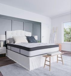 a white bed sitting on top of a wooden floor next to a window with lots of windows