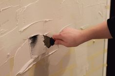 a person painting a wall with white paint and a brush in their hand on the wall