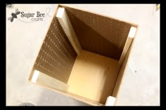 an open cardboard box sitting on top of a white floor with the bottom half missing