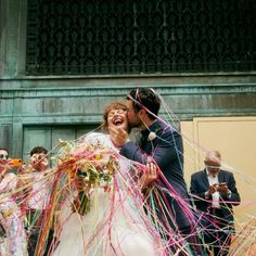 a bride and groom kissing while confetti is thrown around them