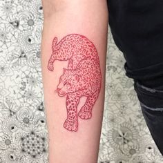 a red ink drawing of a leopard on the right arm and leg, with flowers in the background