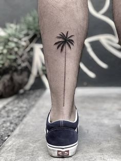 a man's leg with a small palm tree tattoo on it