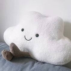 a white cloud pillow sitting on top of a bed next to a stuffed animal toy