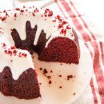 a chocolate cake with white frosting and red sprinkles on top is sitting on a plate