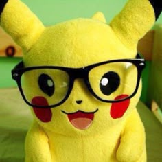 a yellow stuffed animal with glasses on top of it's head sitting on a bed