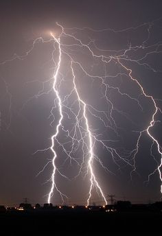 lightning strikes across the night sky over a city