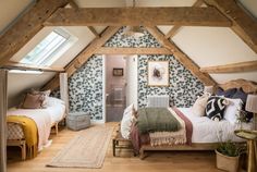 an attic bedroom with two beds and a rug on the floor in front of it