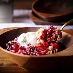 a wooden bowl filled with ice cream and cranberry sauce on top of a table