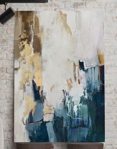 an abstract painting hangs on the wall above two stools in front of a brick wall