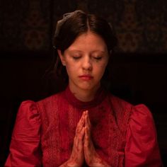 a woman in a red dress is praying with her eyes closed and hands clasped together