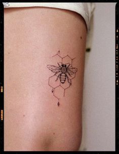 a bee tattoo on the side of a woman's thigh with honeycombs