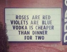 a sign on the side of a building that says roses are red violets are blue vodka is cheaper than dinner for two