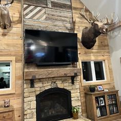 a living room with a fireplace, television and deer head mounted on the wall above it