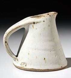 a white pitcher sitting on top of a table next to a black and white background