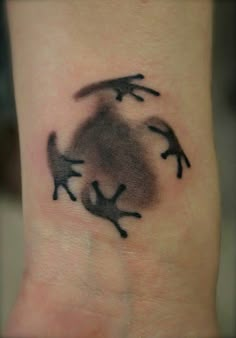 a tattoo on the wrist of a person with an upside down frog design in black ink