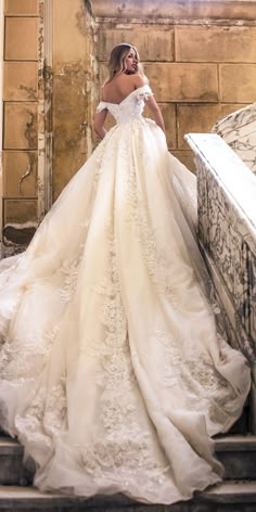 a woman in a wedding dress is walking up some stairs with her hand on her hip