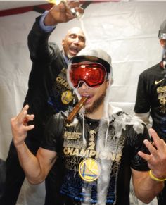 a man wearing goggles and drinking champagne in front of two other men with skis on