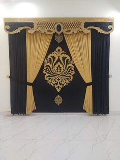 a black and gold curtain with an ornate design on the side, in front of a white wall