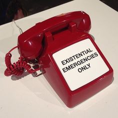 an old fashioned telephone sitting on top of a white table next to a sign that says existent emergency only