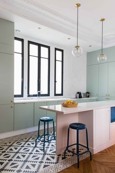 a kitchen with two stools in front of an island and three lights hanging from the ceiling